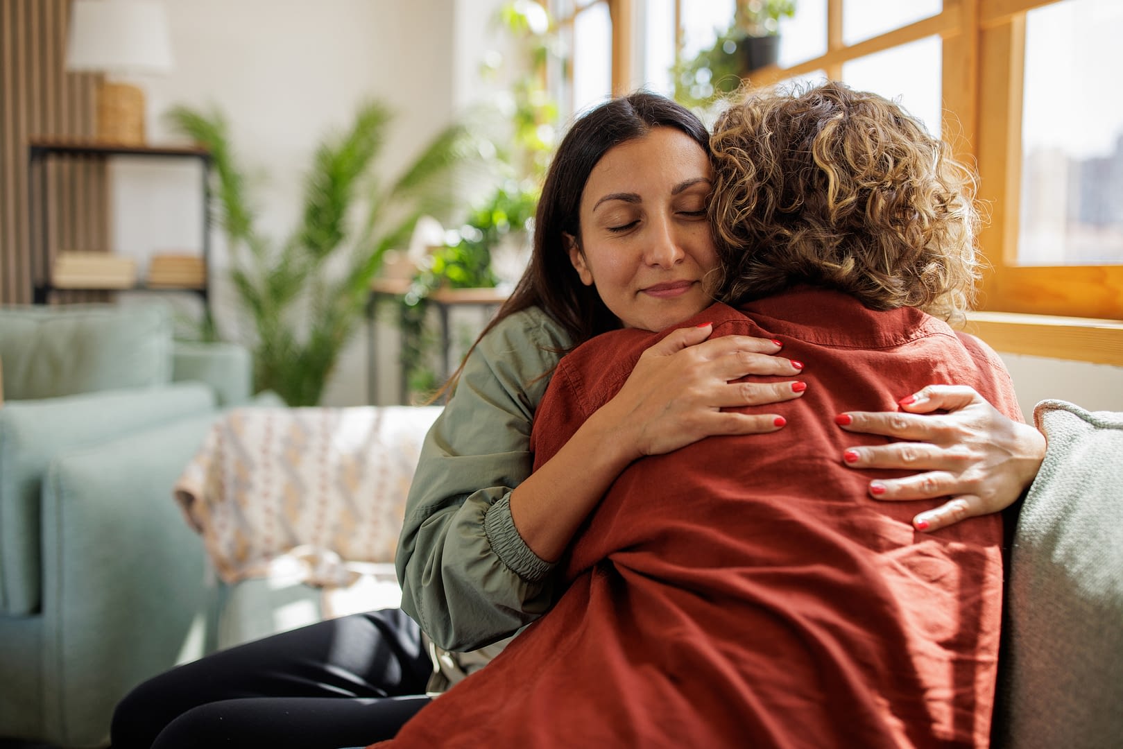 Two female friends supporting each other in the living room of an apartment