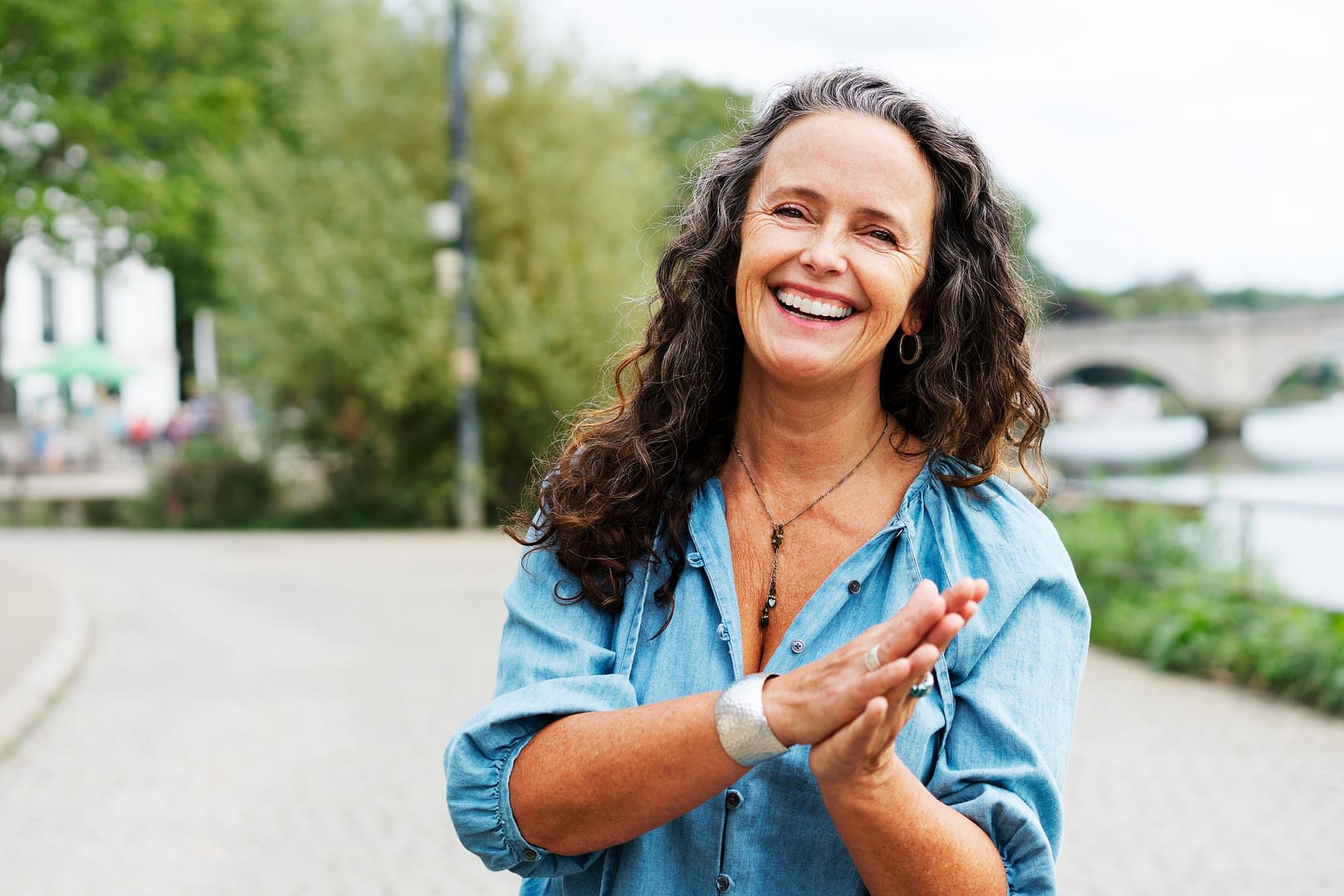 Woman with hands together looking at camera, smiling