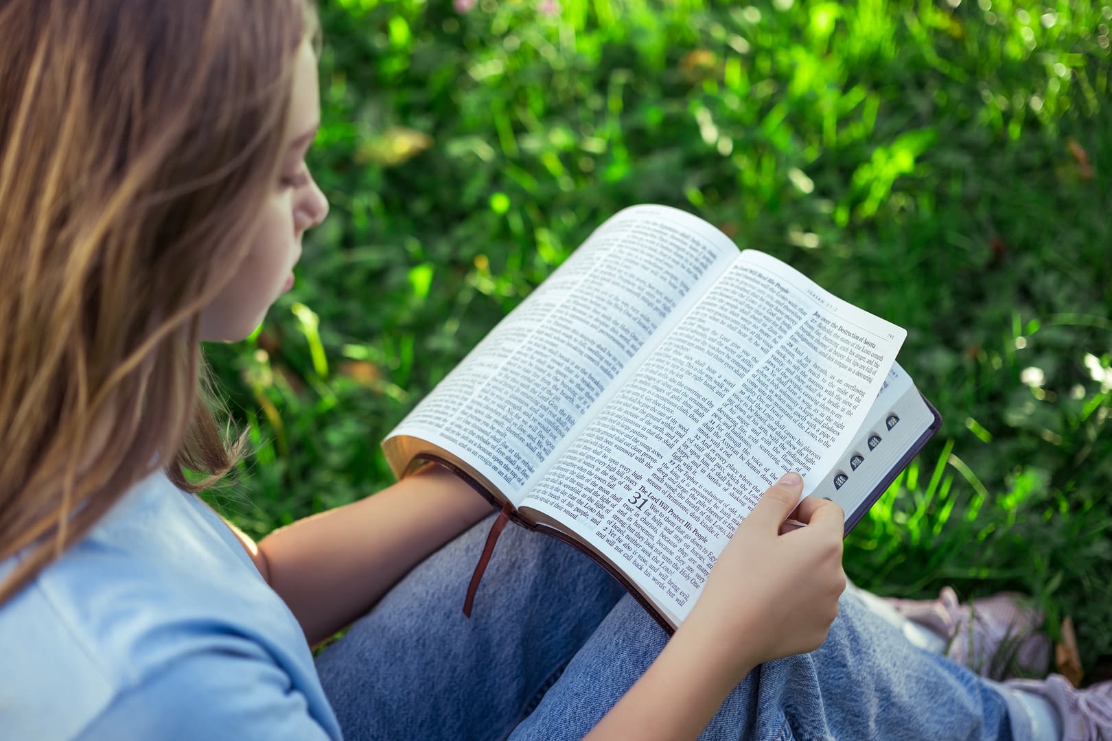 Young girl reading Bible outdoors
