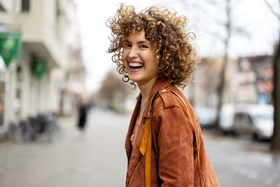 Beautiful woman walking outdoors looking behind and laughing Encouragement for Singles