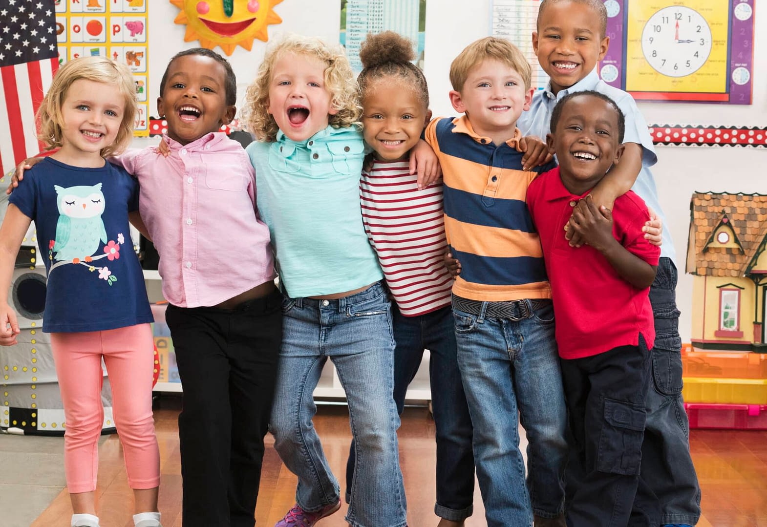 Portrait of smiling students hugging in a line in a classroom