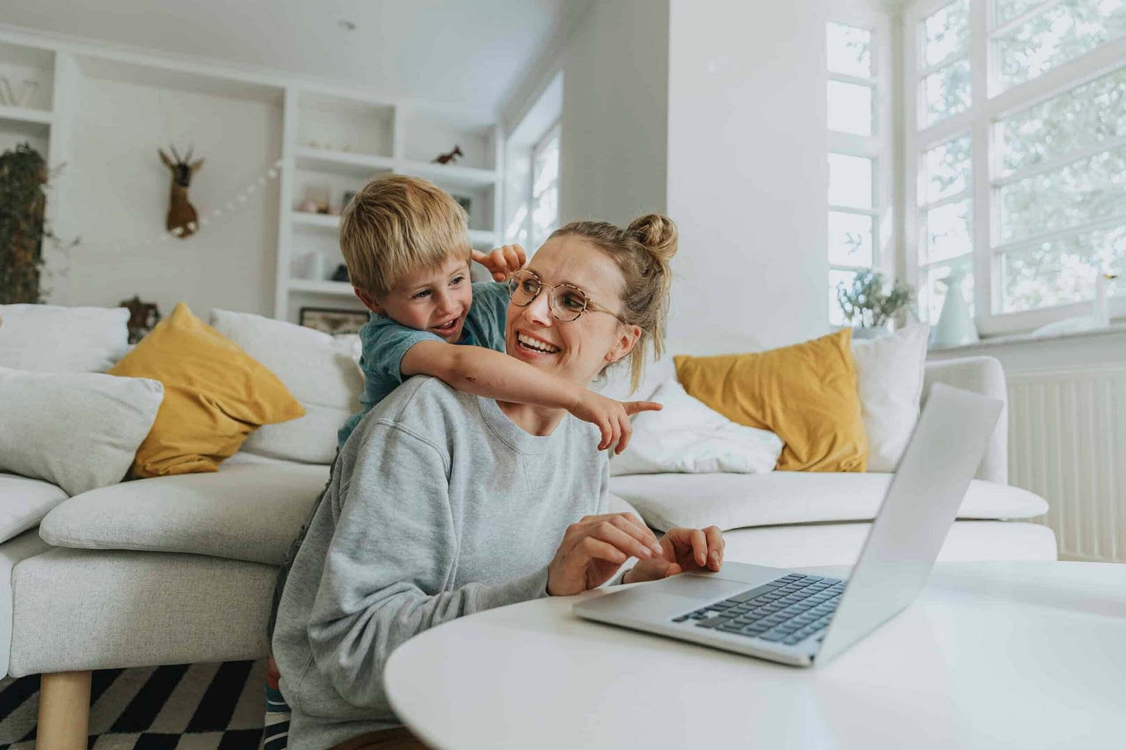 Boy pointing at laptop while standing behind mother