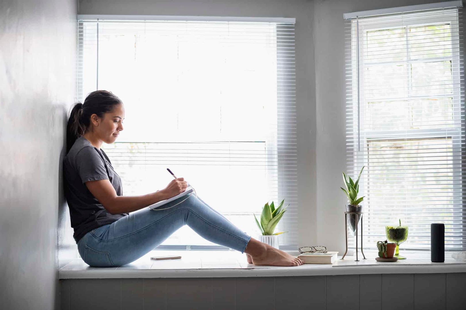 Woman sitting in widow seat writing