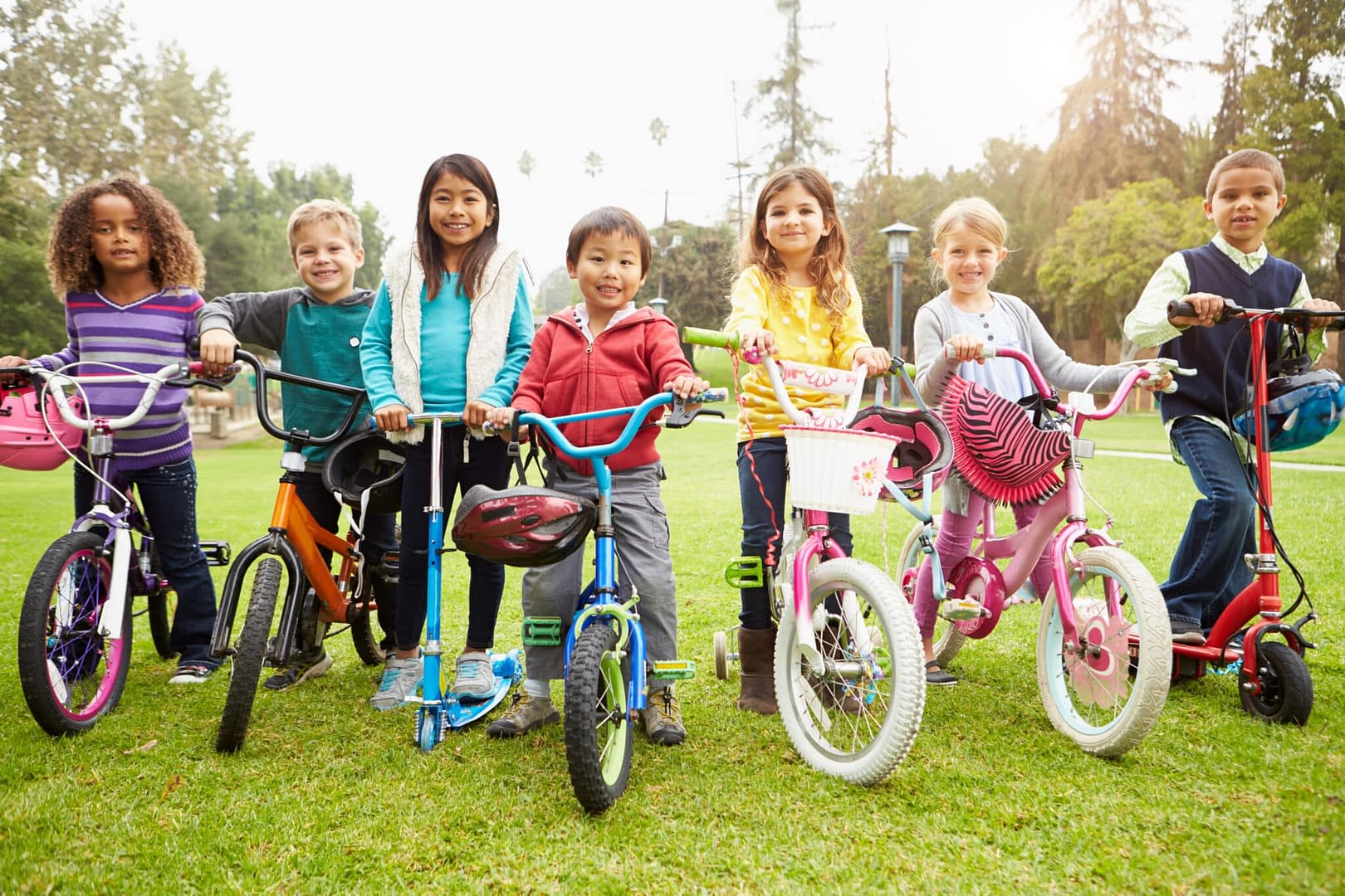 Young Children With Bikes And Scooters In Park