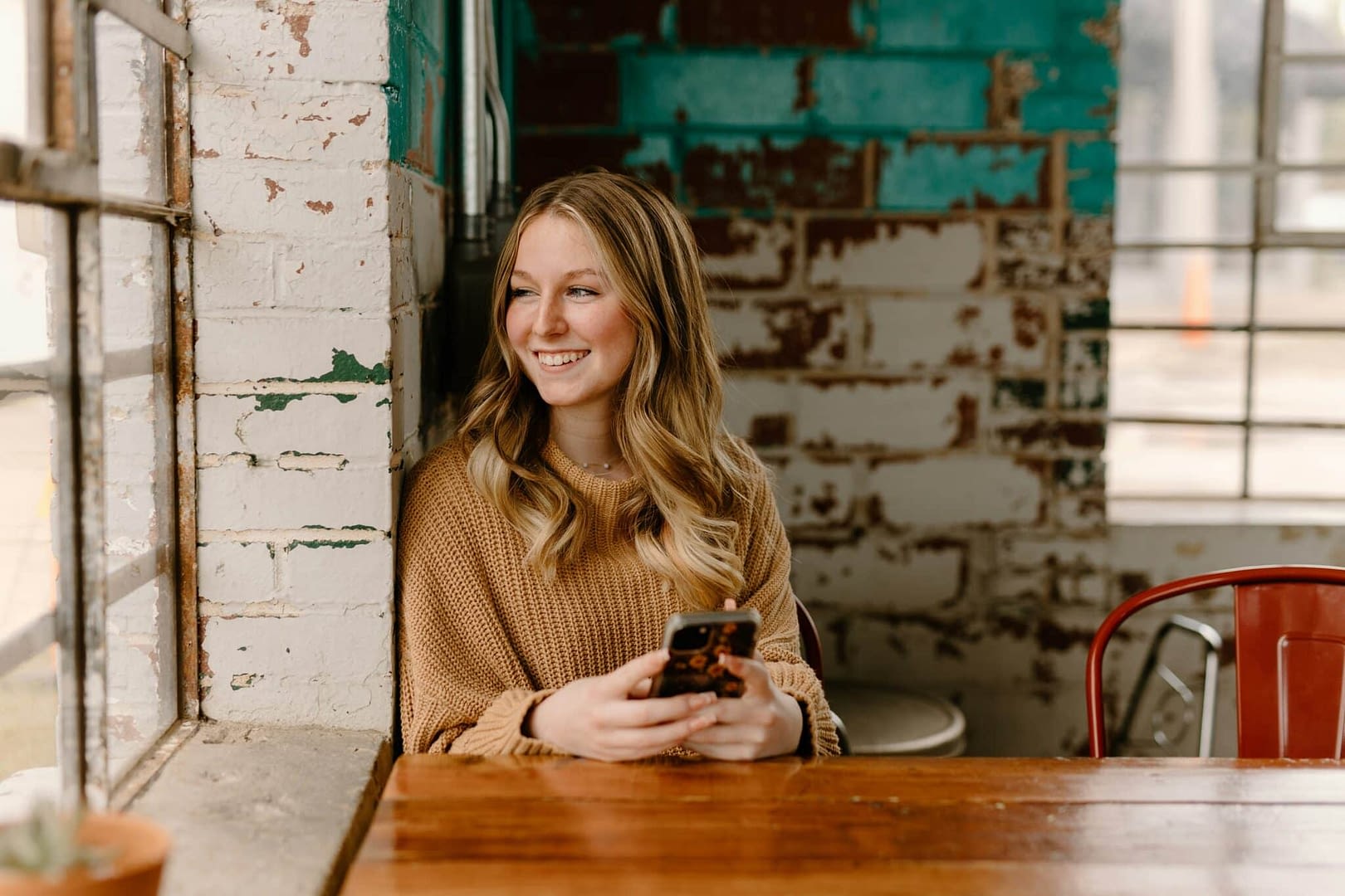 young adult woman sitting at coffee shop looking out window