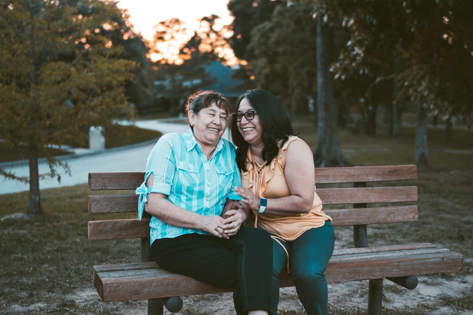 two women laughing on park bench