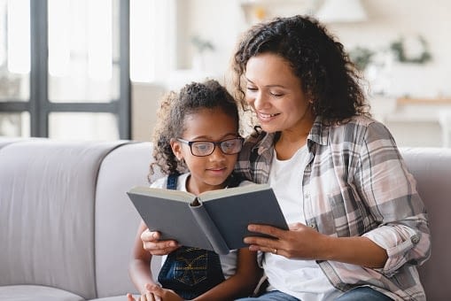 mother reading with daughter on couch