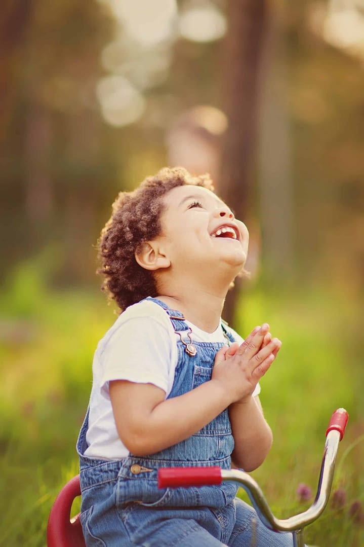 boy looking up to the sky with hands folded