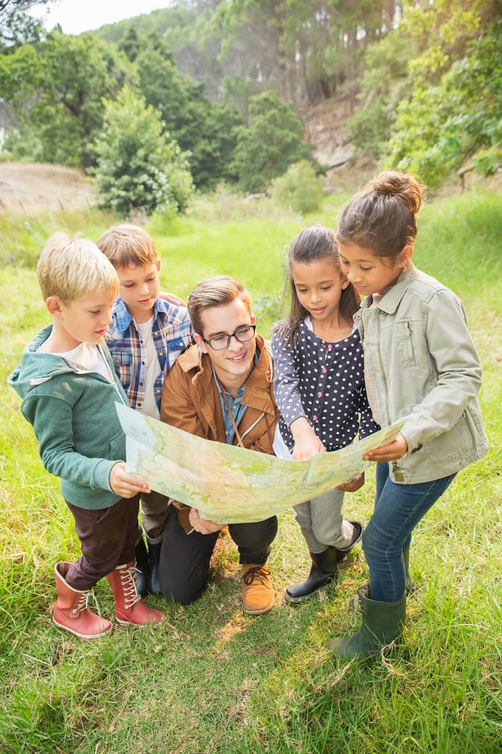 Students and teacher reading map in field