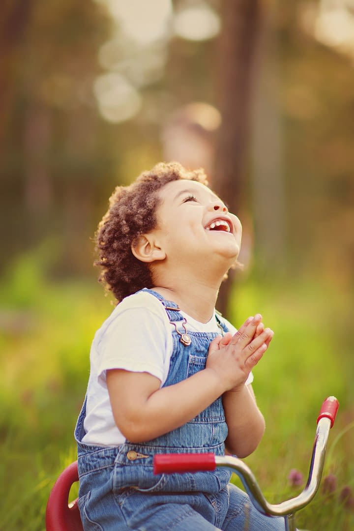 boy looking up to the sky with hands folded