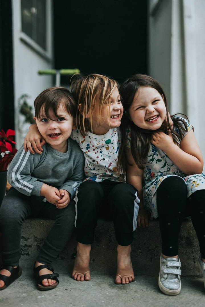 three small friends hugging on stoop