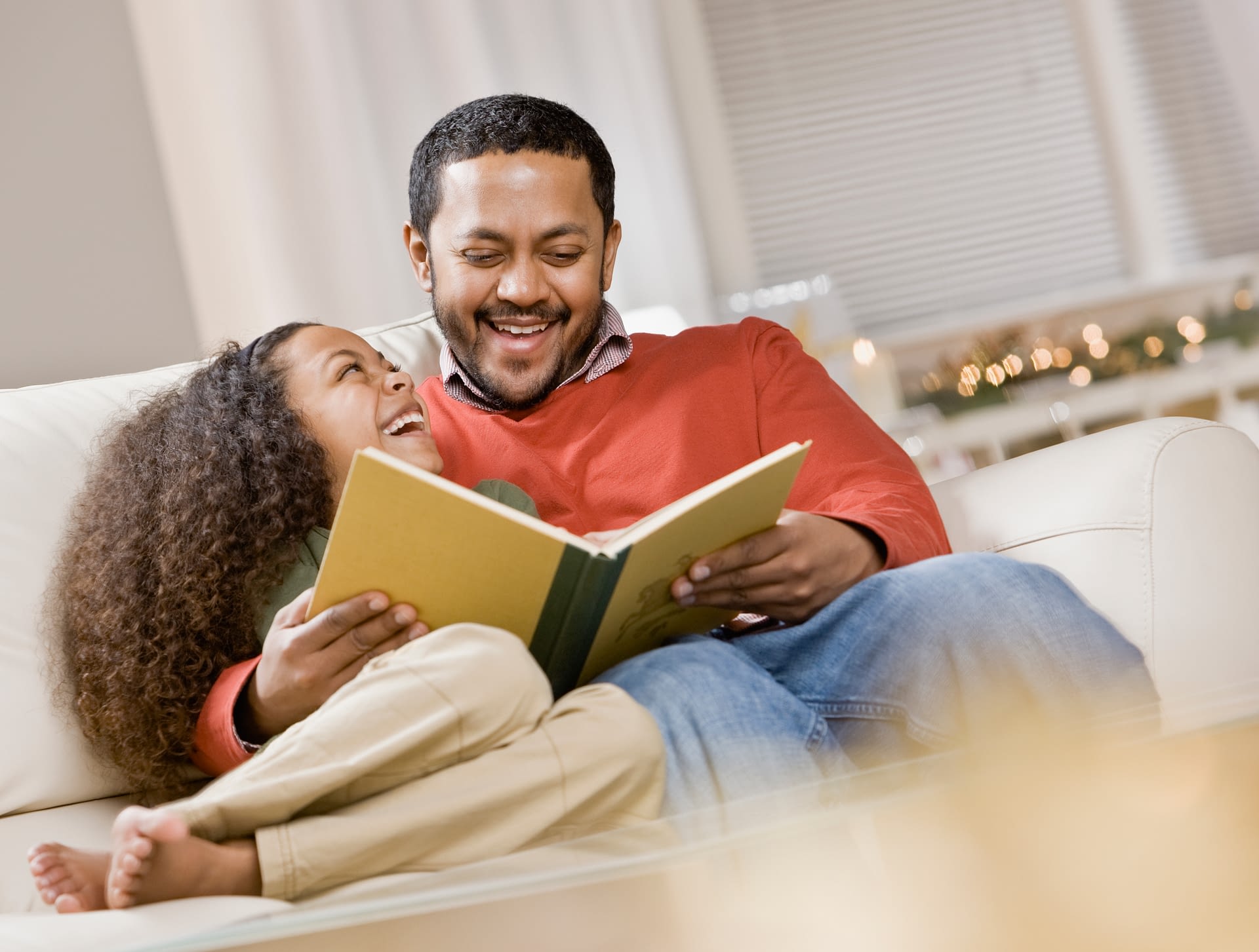 father and daughter reading on the couch